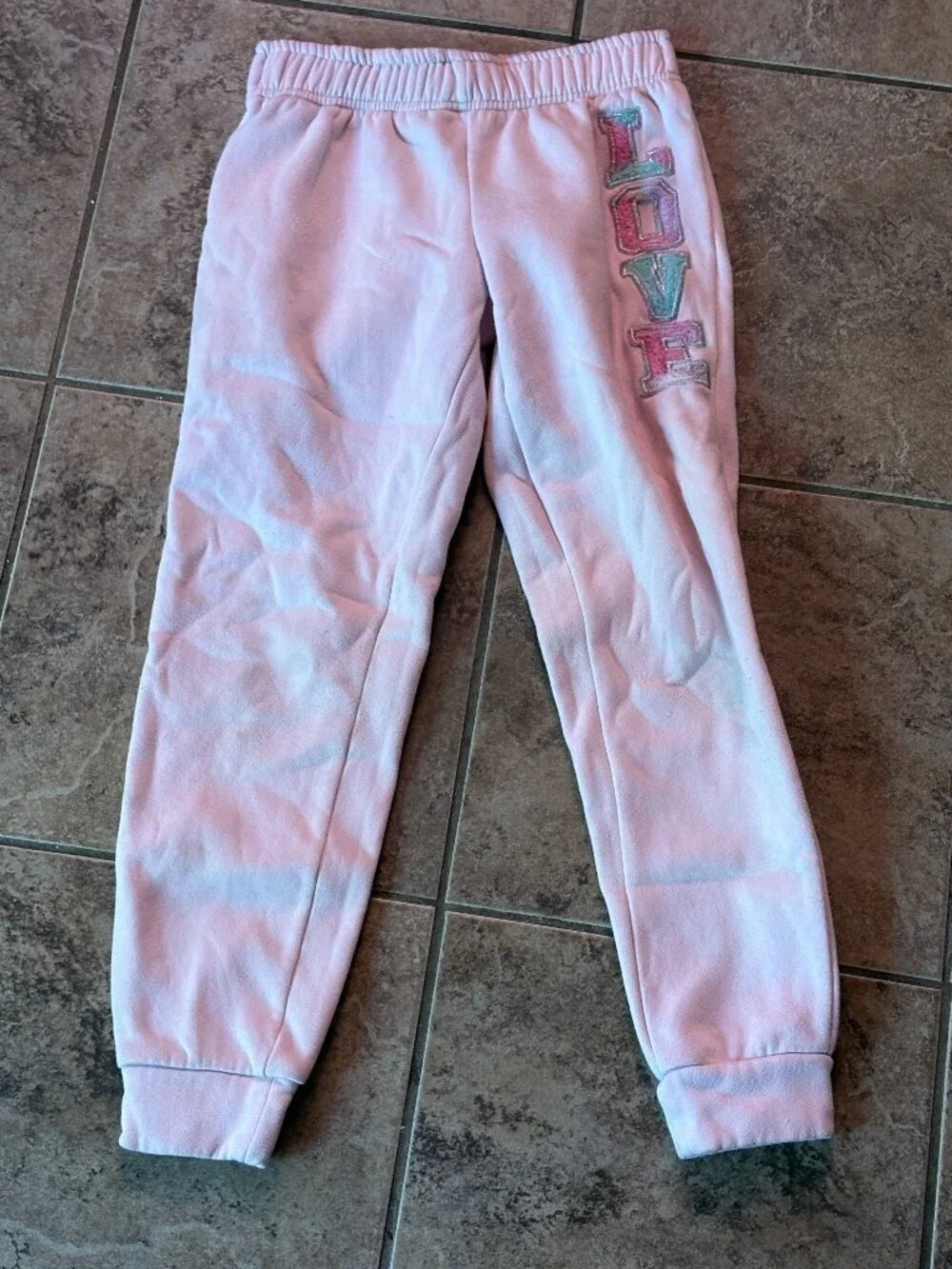 Pink tie-dye sweatpants with 'LOVE' graphic